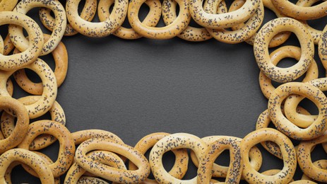 Photo of Frame of many delicious ring shaped Sushki (dry bagels) on dark blue background, top view. Space for text
