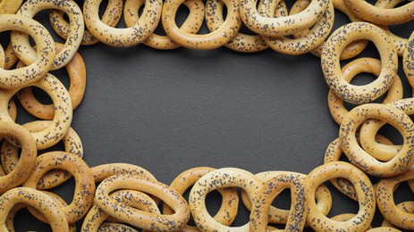 Frame of many delicious ring shaped Sushki (dry bagels) on dark blue background, top view. Space for text