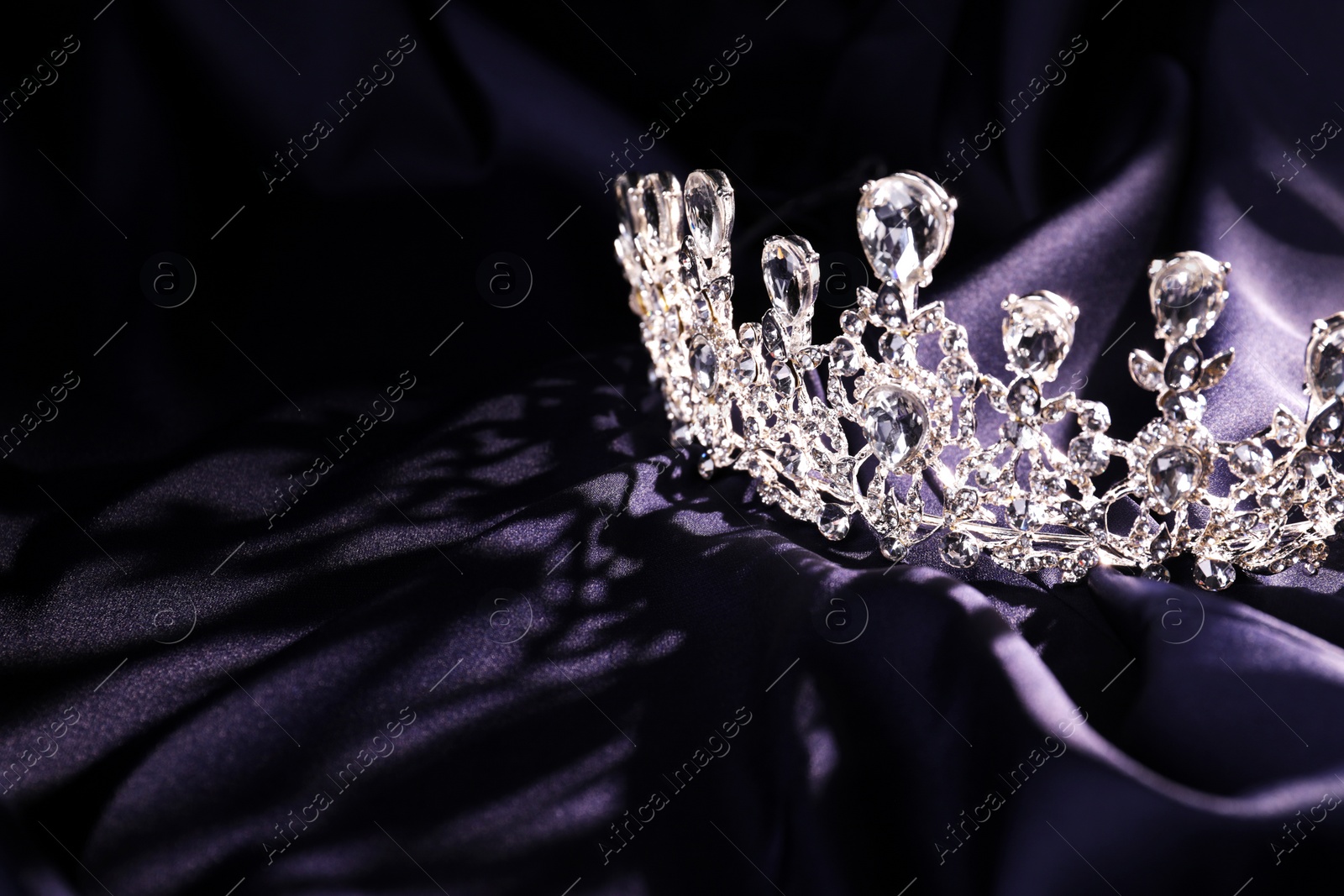 Photo of Beautiful silver tiara with diamonds on dark cloth. Space for text