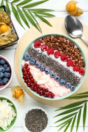 Photo of Tasty smoothie bowl with fresh berries and granola served on white wooden table, flat lay