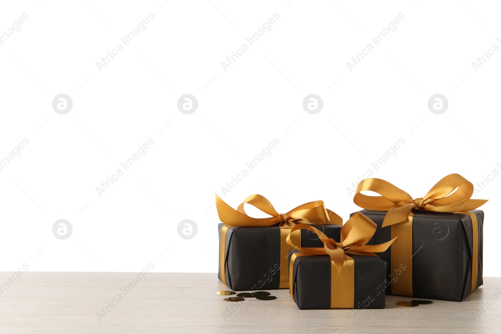 Photo of Three black gift boxes on white wooden table. Space for text