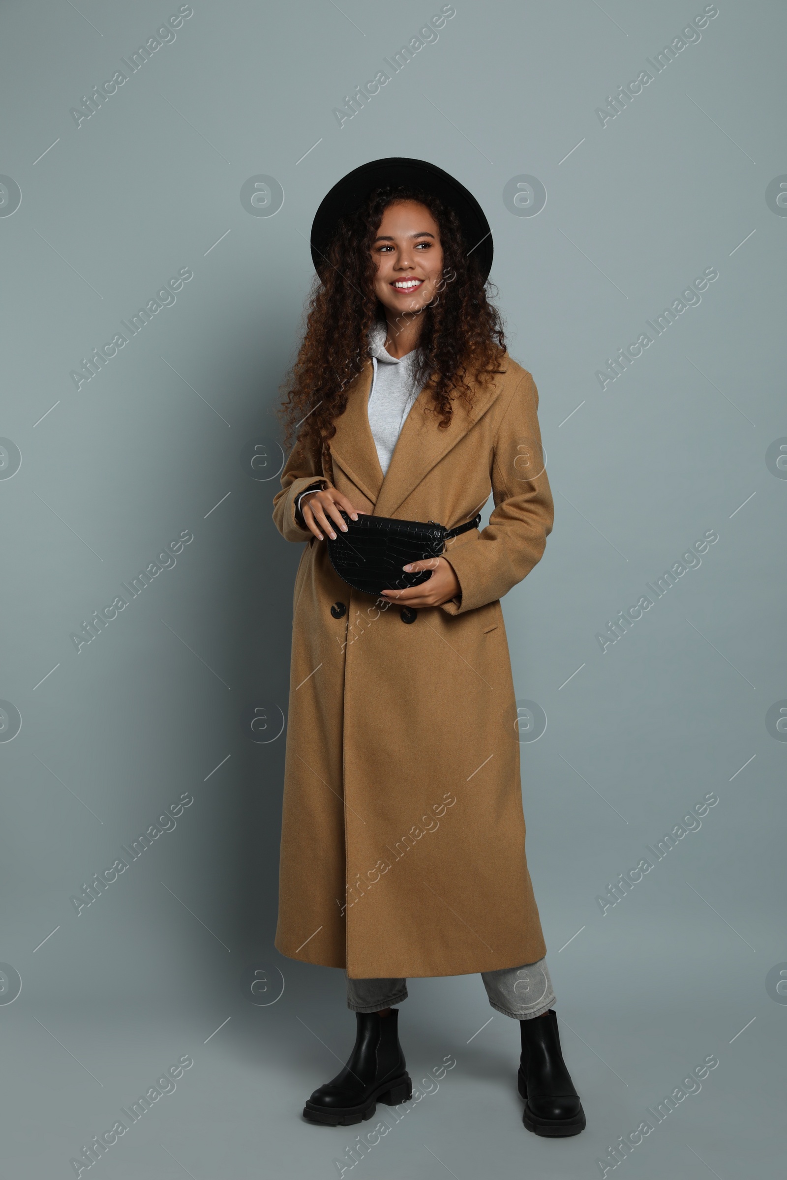 Photo of Beautiful African American woman with stylish waist bag on grey background