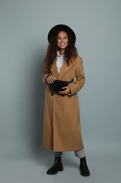 Photo of Beautiful African American woman with stylish waist bag on grey background