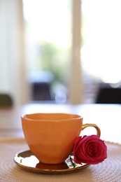 Photo of Cup of hot drink and red rose on table indoors. Space for text