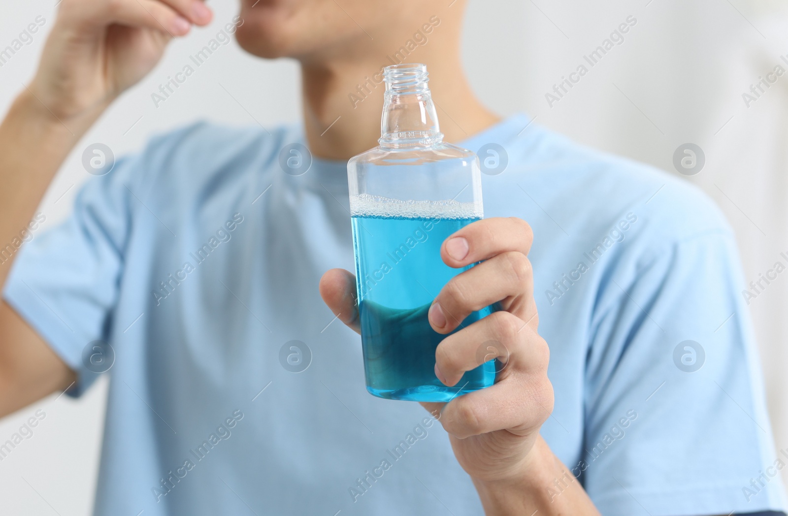 Photo of Young man using mouthwash indoors, closeup view