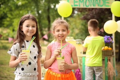 Photo of Little girls with natural lemonade in park