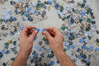 Photo of Man playing with puzzles on floor, top view