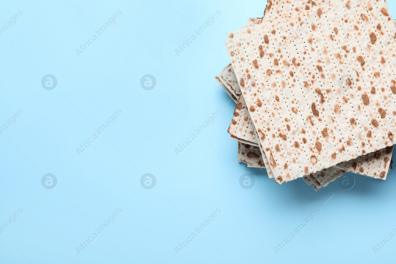 Photo of Stack of traditional matzos on light blue background, top view. Space for text
