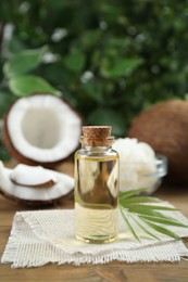 Bottle of organic coconut cooking oil and leaf on wooden table
