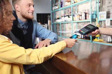 Clients using credit card machine for non cash payment in cafe