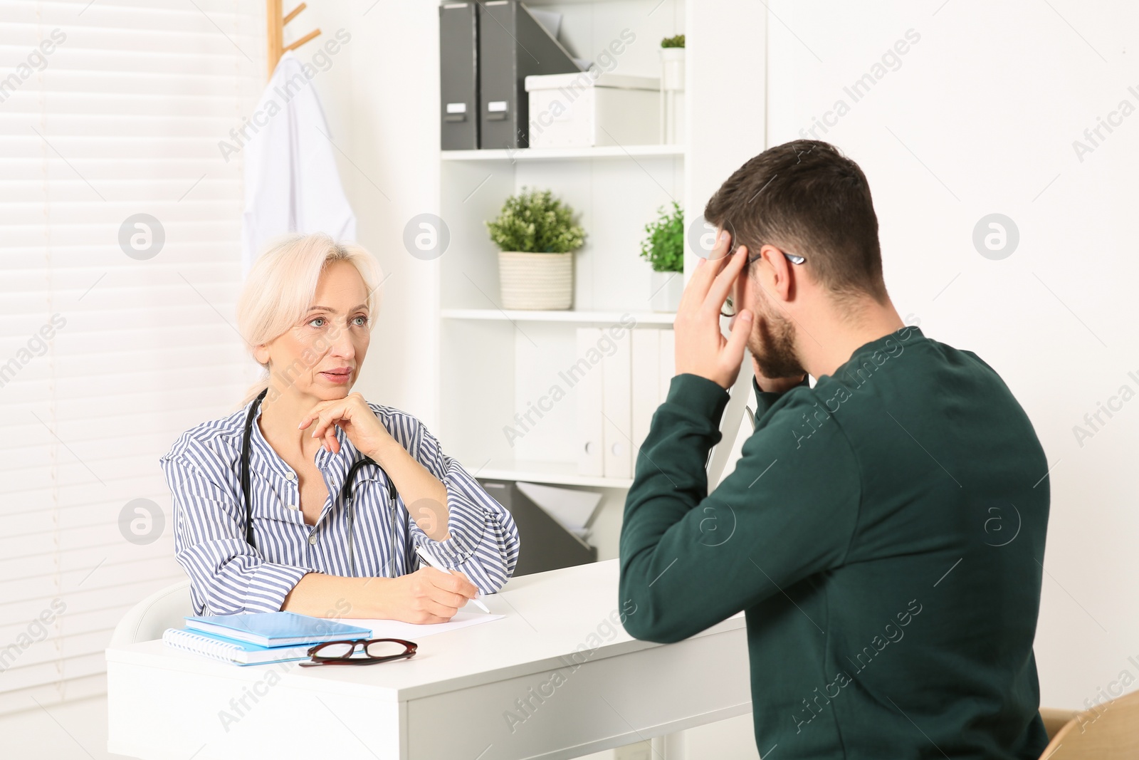 Photo of Doctor consulting patient at white table in clinic