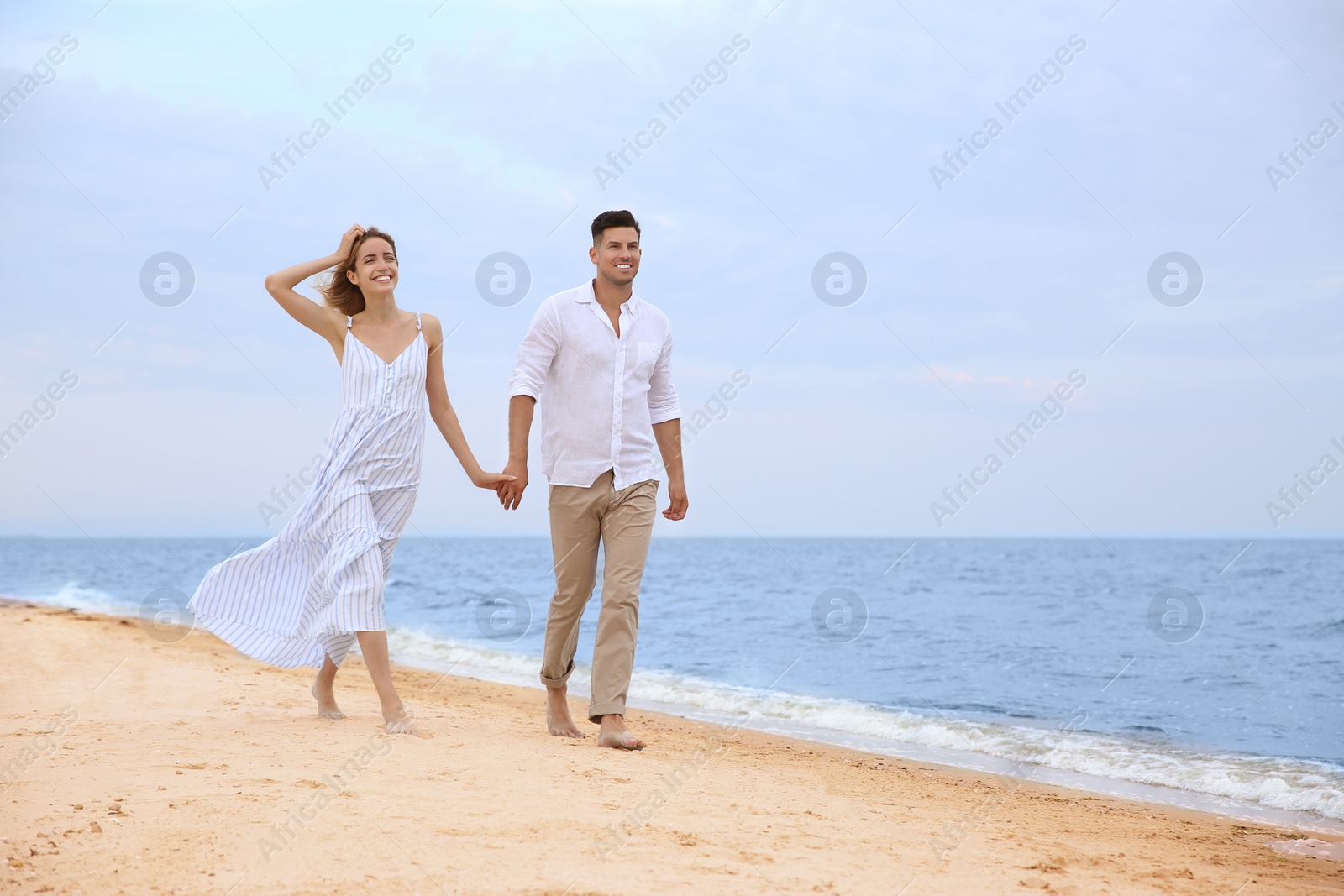 Photo of Happy couple having romantic walk on beach. Space for text