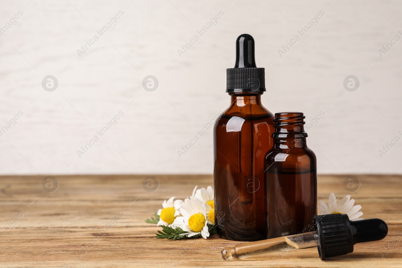 Photo of Composition with bottles of chamomile essential oil on table. Space for text