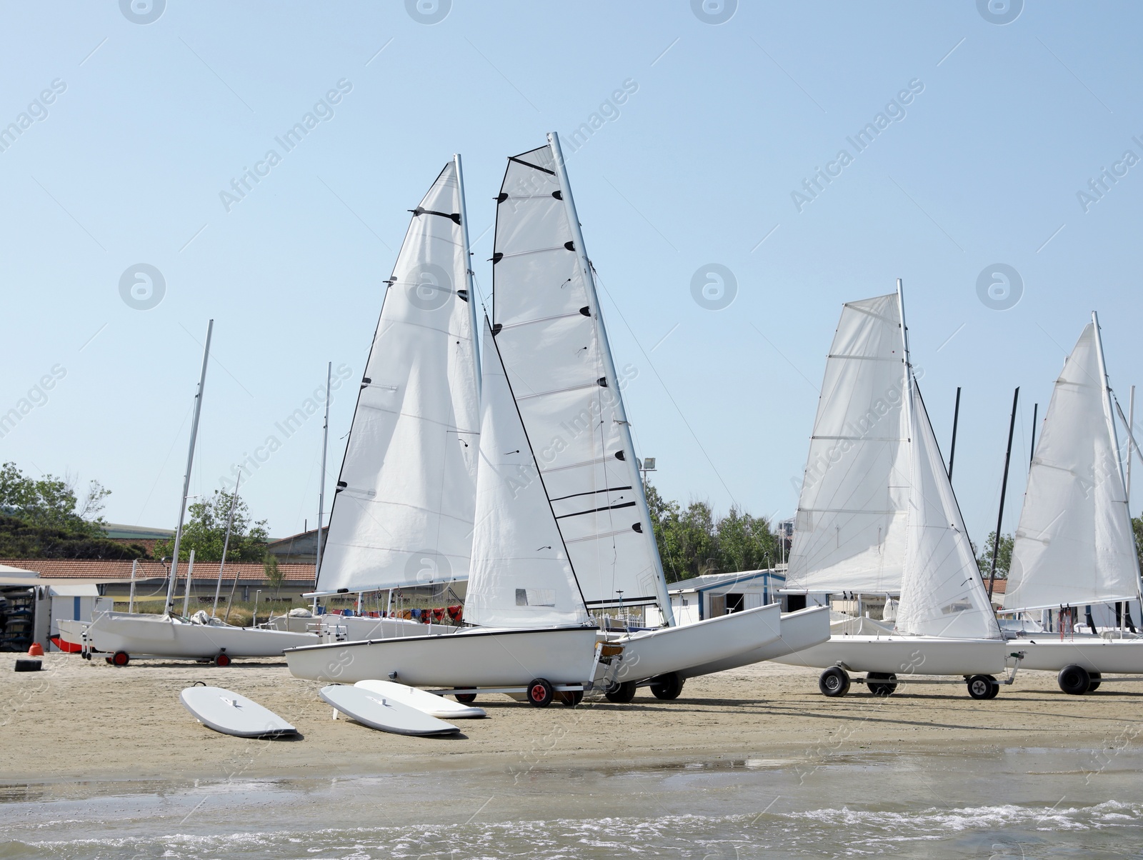 Photo of Seacoast with surf boards and modern yachts on sunny day