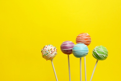 Many bright delicious cake pops on color background. Space for text