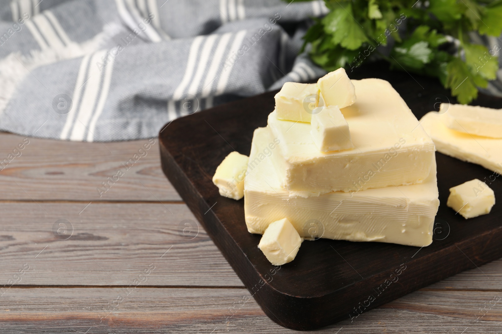 Photo of Pieces of tasty butter on wooden table. Space for text