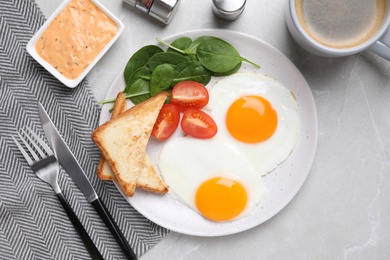 Photo of Tasty breakfast with fried eggs, toasts and coffee served on light grey table, flat lay