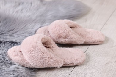 Photo of Pink soft slippers on light wooden floor at home, closeup