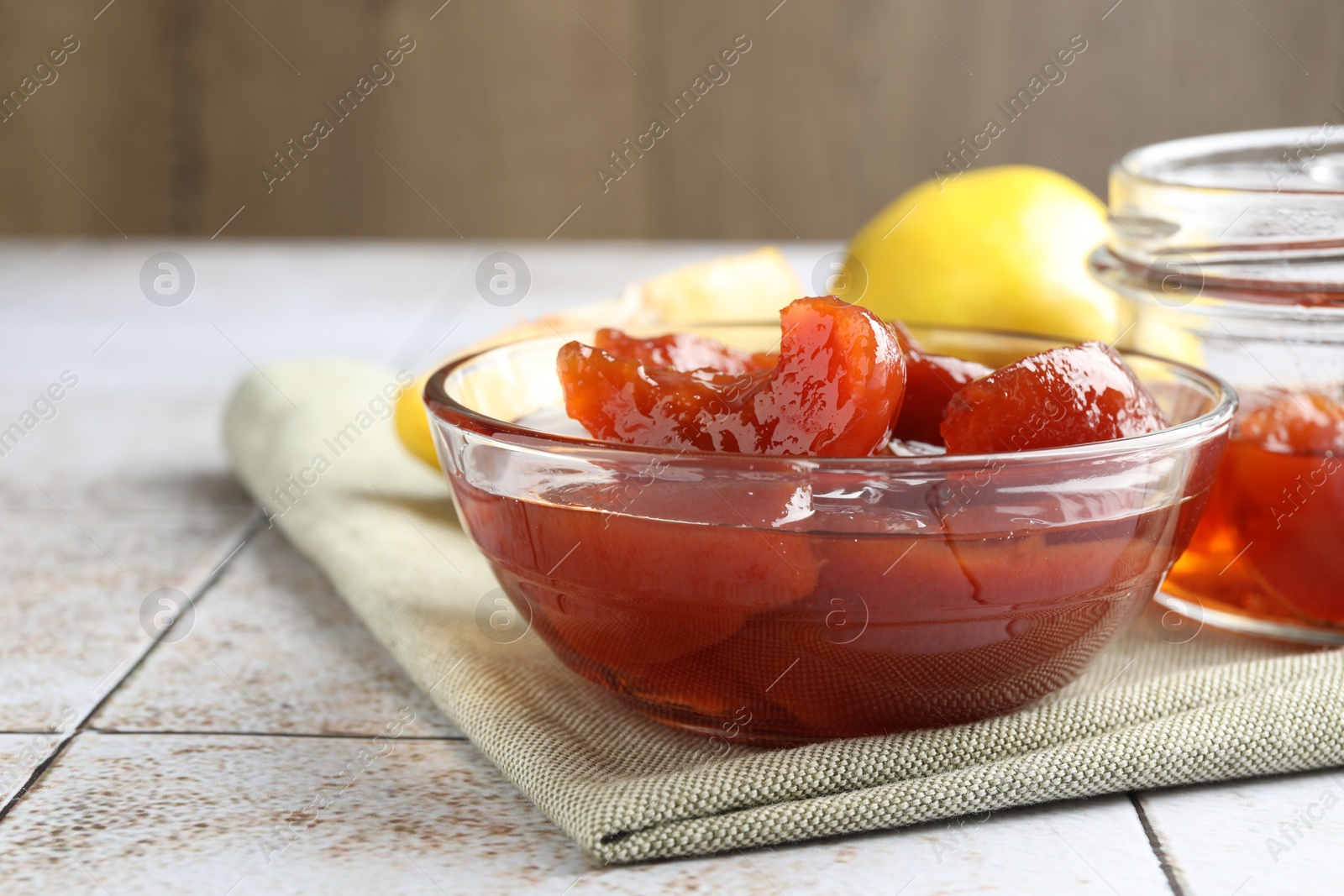 Photo of Tasty homemade quince jam in bowl on tiled table, closeup. Space for text
