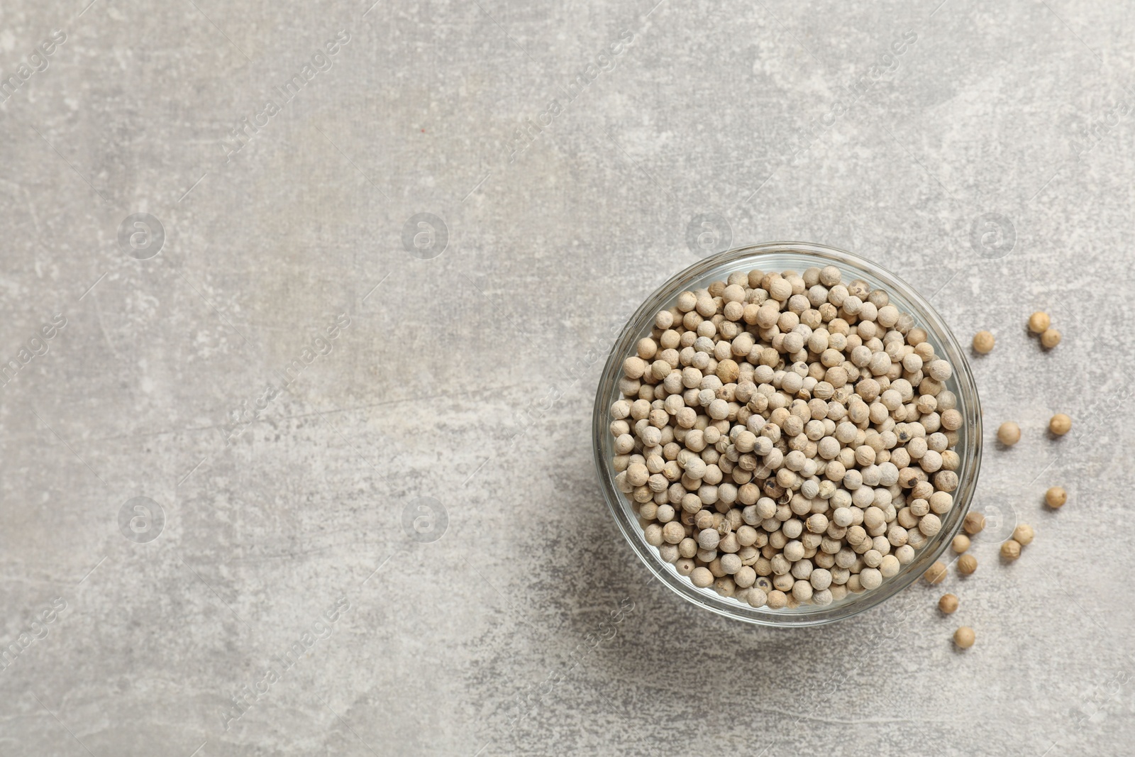 Photo of Aromatic spice. White pepper in bowl on light grey table, top view. Space for text