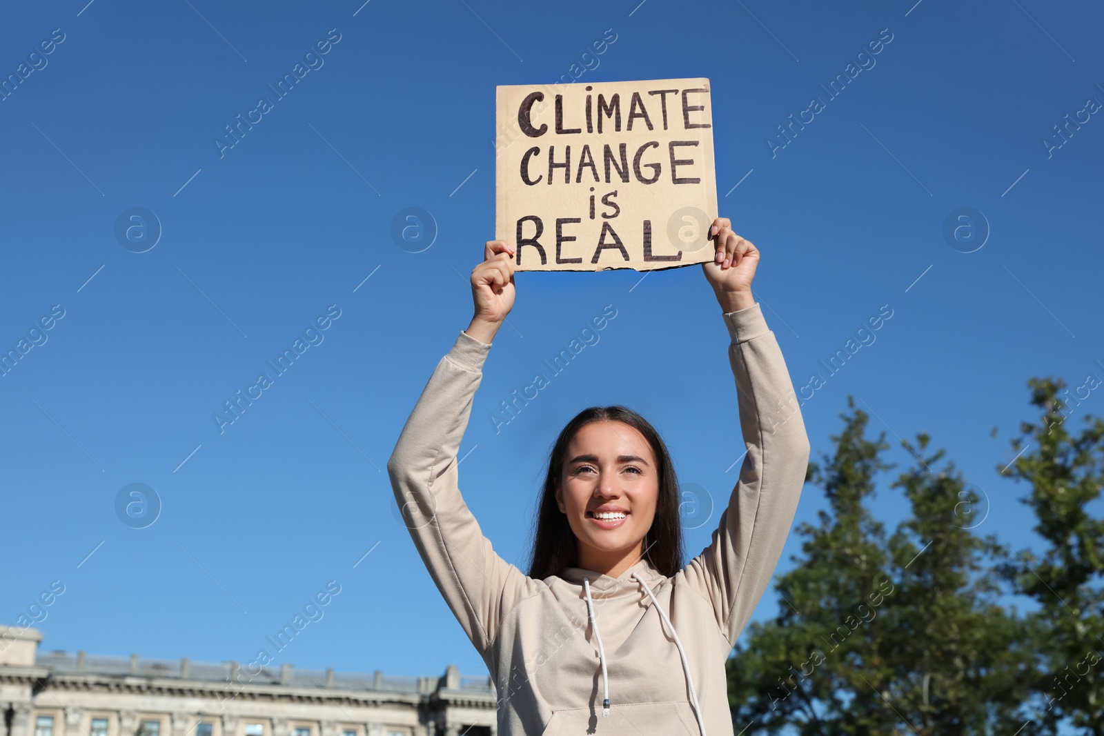 Photo of Young woman with poster protesting against climate change outdoors