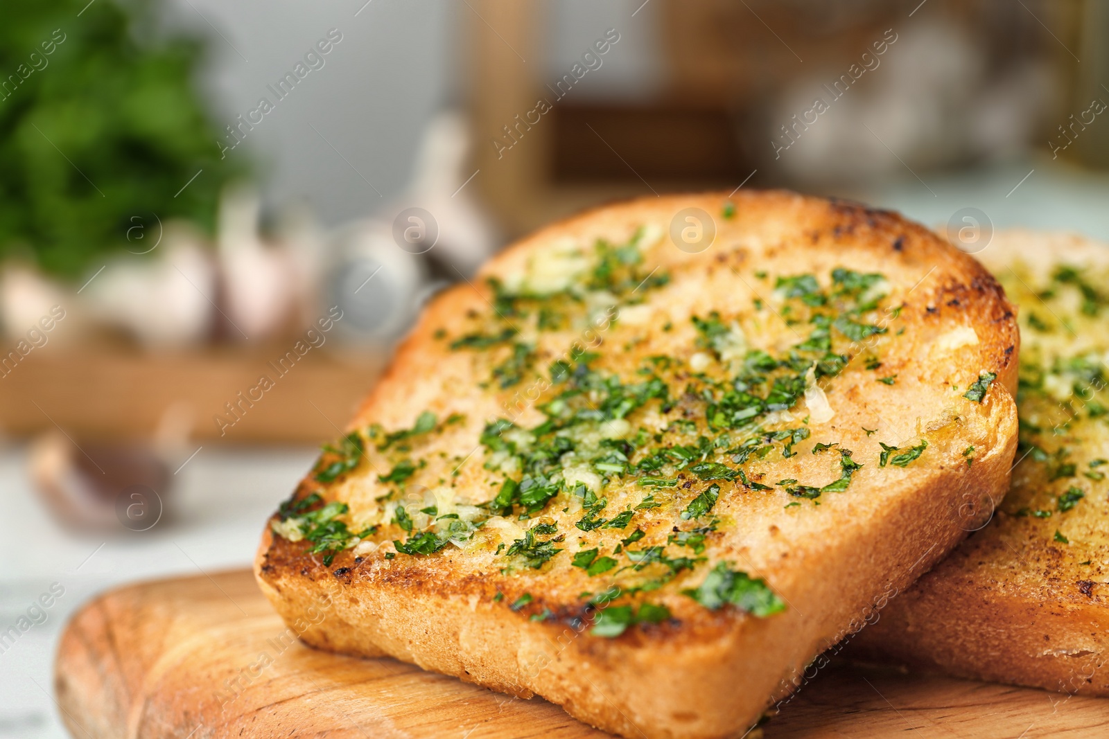 Photo of Slices of toasted bread with garlic and herbs on wooden board, closeup