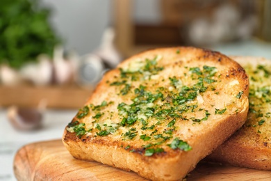 Slices of toasted bread with garlic and herbs on wooden board, closeup