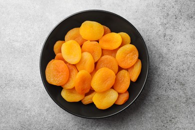 Photo of Plate of tasty apricots on grey table, top view. Dried fruits