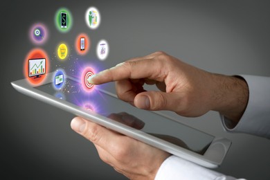 Image of Marketing. Man touching virtual icon over tablet against grey background, closeup