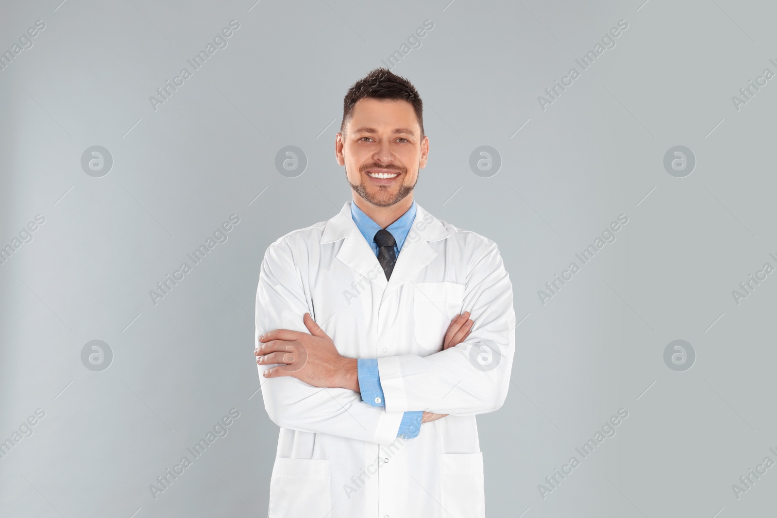 Photo of Happy man in lab coat on light grey background