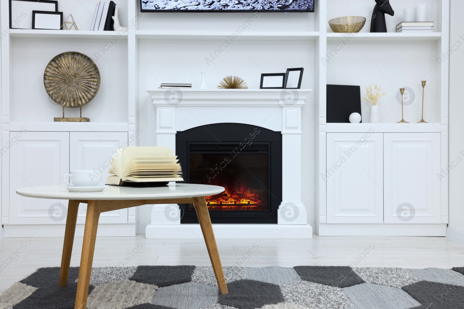 Photo of Stylish room with beautiful fireplace and book on table. Interior design