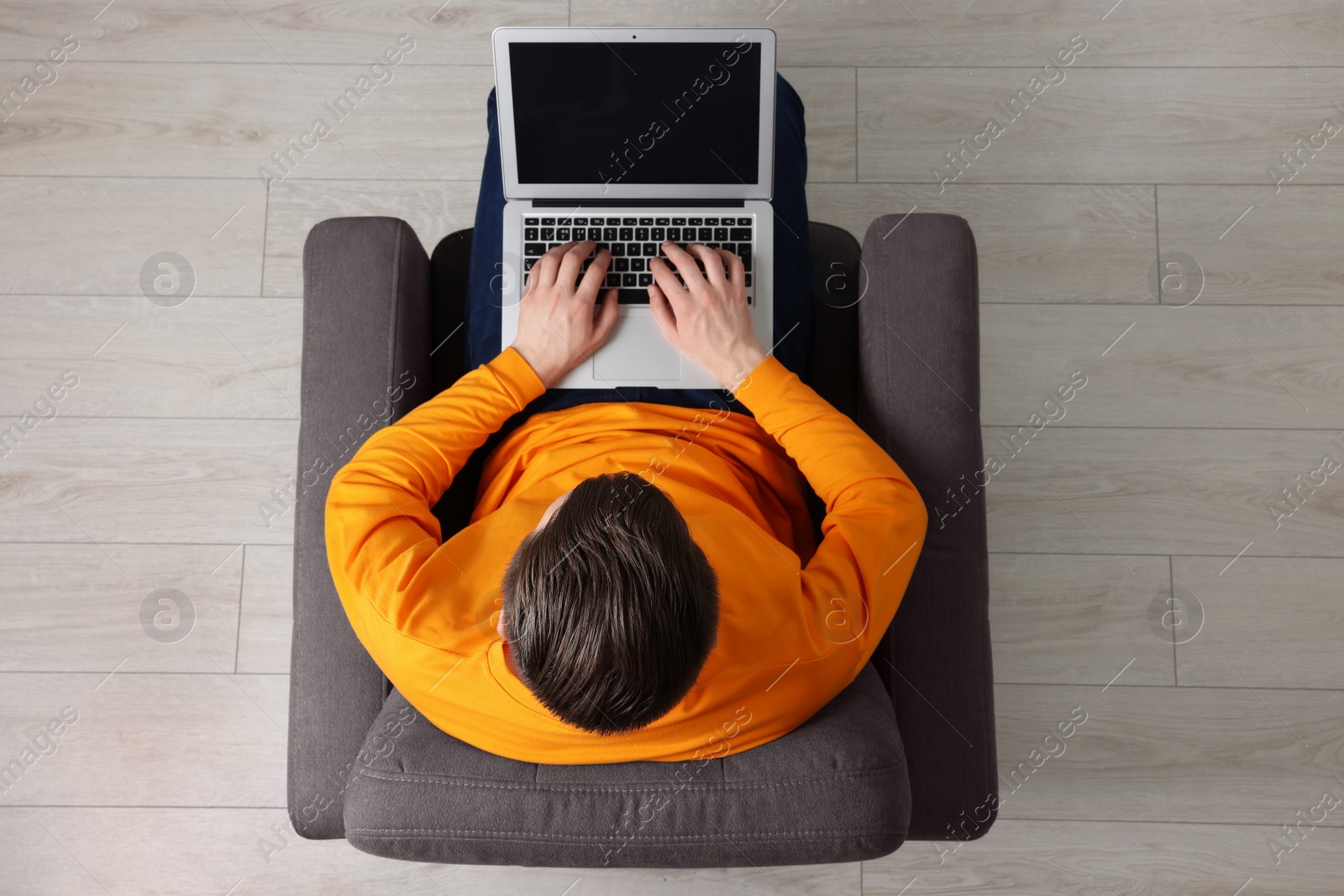 Photo of Man working with laptop in armchair, top view