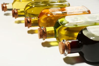 Vegetable fats. Different cooking oils in glass bottles on white background, closeup. Space for text