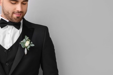 Groom with boutonniere on light grey background, space for text. Wedding accessory
