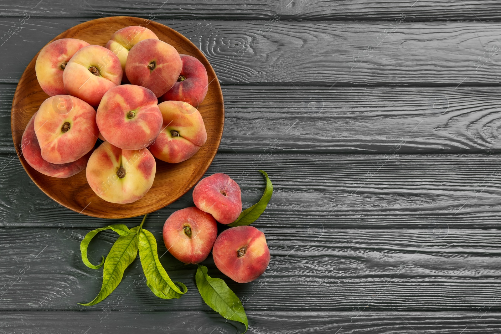 Photo of Fresh ripe donut peaches on grey wooden table, flat lay. Space for text