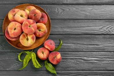 Photo of Fresh ripe donut peaches on grey wooden table, flat lay. Space for text