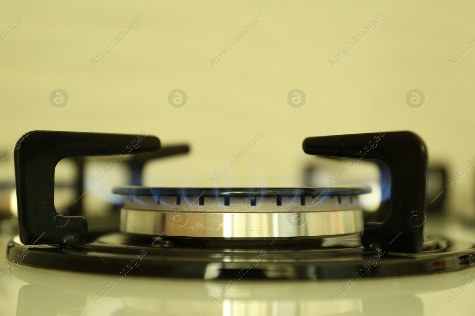Photo of Gas burner of modern stove with burning blue flame, closeup