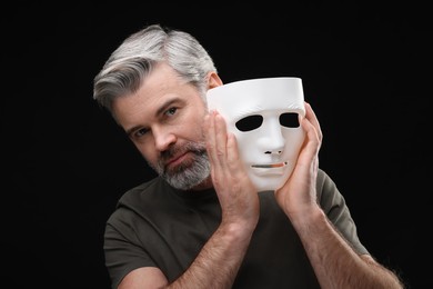 Photo of Multiple personality concept. Man with mask on black background