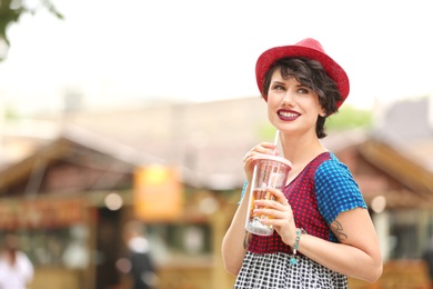 Young woman with cup of tasty lemonade outdoors