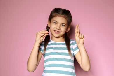 Photo of Little girl using sign language on color background