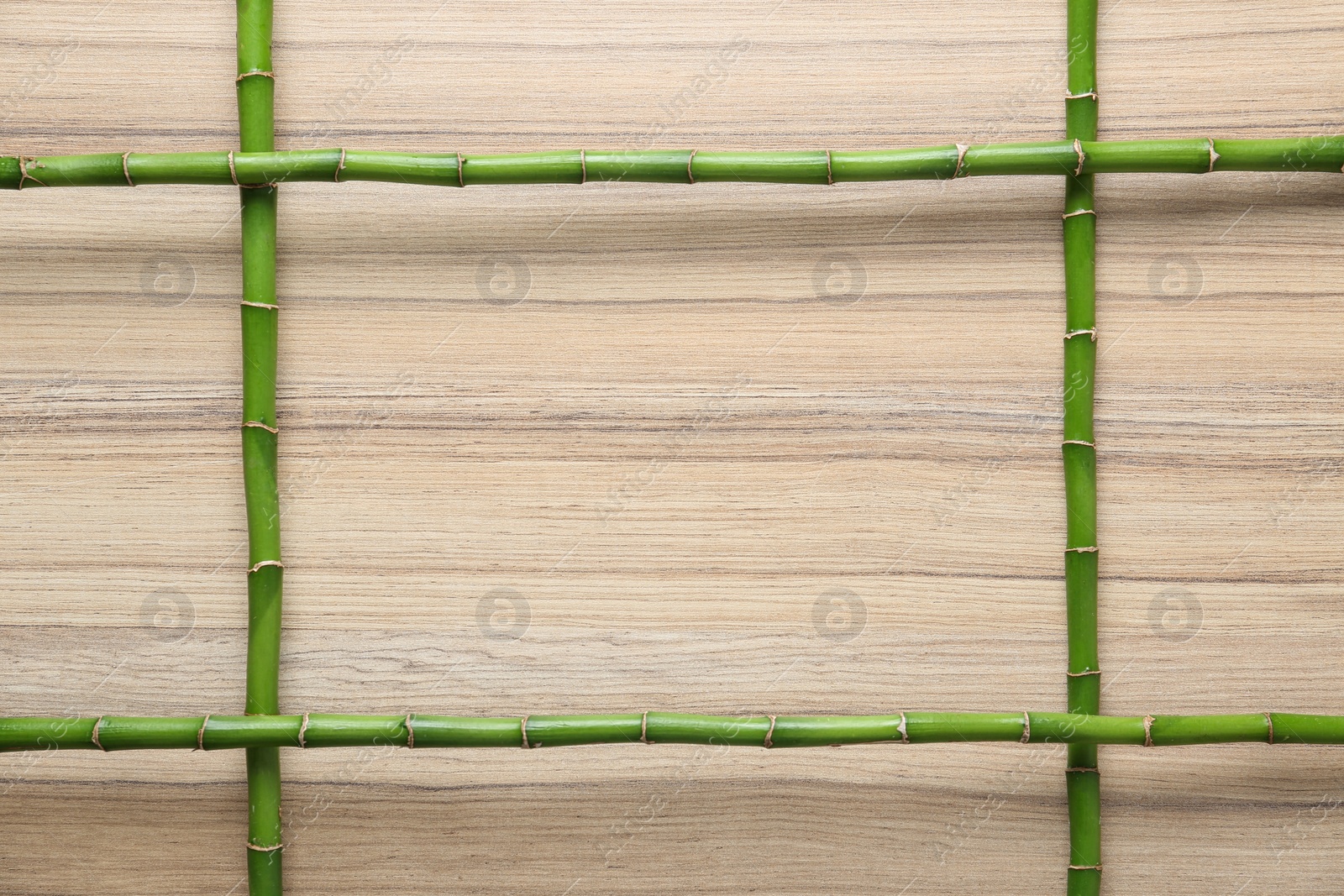 Photo of Frame made of green bamboo stems on wooden background. Space for text