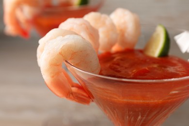 Photo of Tasty shrimp cocktail with sauce in glass on table, closeup