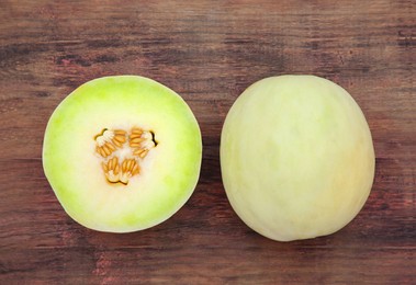 Photo of Whole and cut fresh ripe melons on wooden table, flat lay