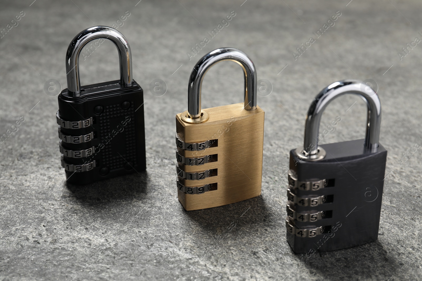 Photo of Locked steel combination padlocks on grey stone table, closeup