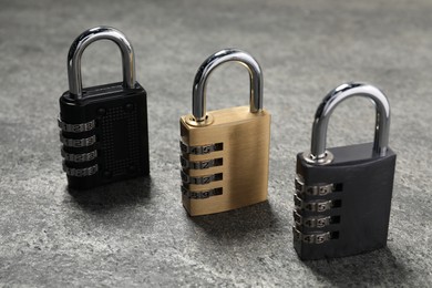 Photo of Locked steel combination padlocks on grey stone table, closeup