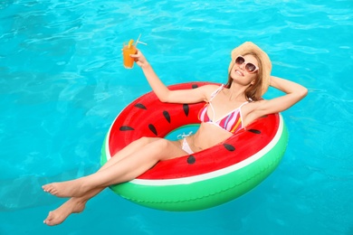 Photo of Young woman with cocktail in pool on sunny day