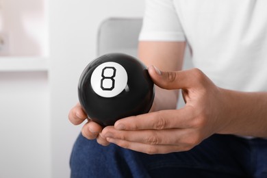 Man holding magic eight ball indoors, closeup