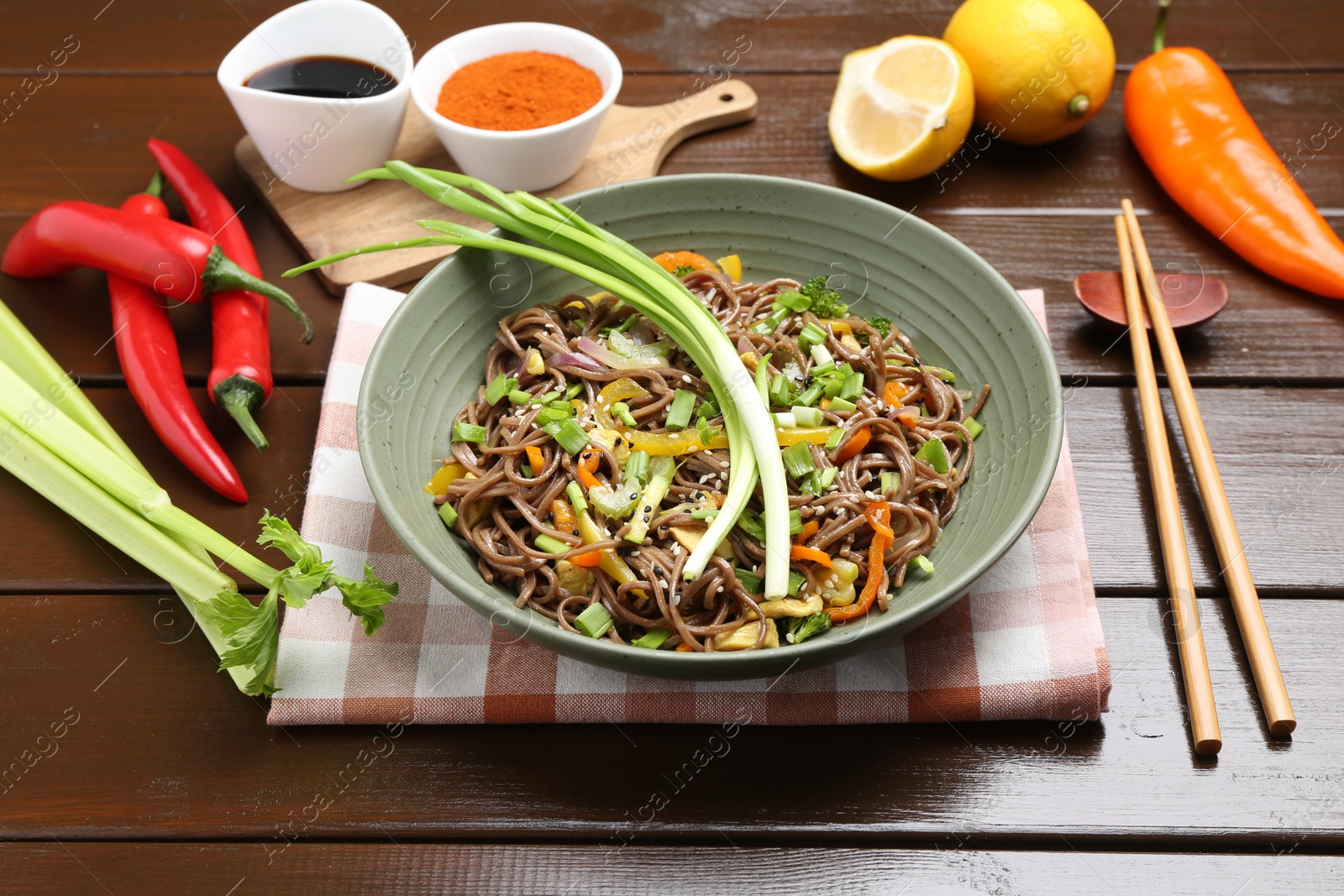 Photo of Stir-fry. Delicious cooked noodles with chicken and vegetables in bowl on wooden table