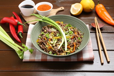 Photo of Stir-fry. Delicious cooked noodles with chicken and vegetables in bowl on wooden table