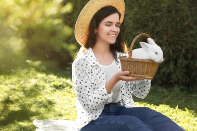 Happy woman with cute rabbit on green grass outdoors